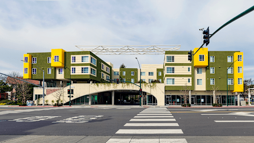 a green and yellow apartment building on the corner of a street