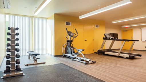a gym with weights and exercise equipment in a room with a window