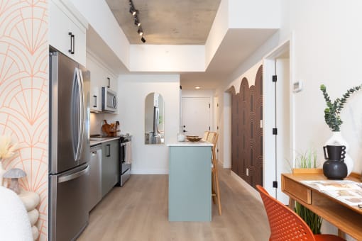 a kitchen and living room with a stainless steel refrigerator and a counter top