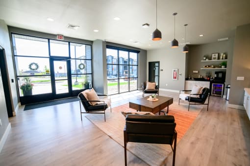 a living room with chairs and a coffee table and large windows