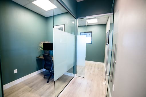 a glass walled office with a desk and a chair