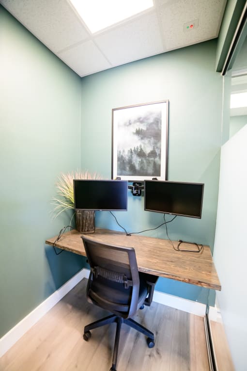 a home office with a desk and two monitors