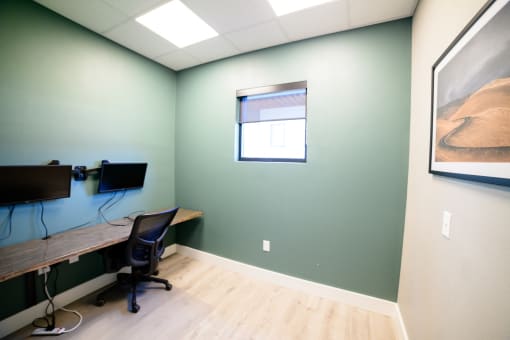 a room with a desk and a monitor and a window