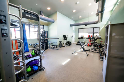 a gym with cardio equipment and weights on the floor