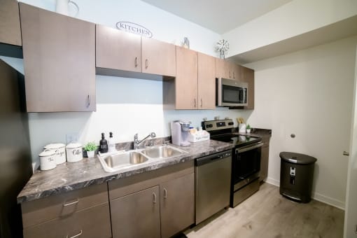 an apartment kitchen with stainless steel appliances and wooden cabinets