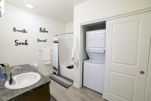 a small bathroom with a sink and a refrigerator and a washer and dryer