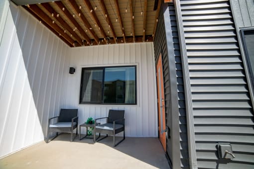 a patio with two chairs and a table under a window