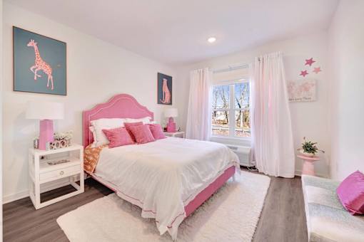 a pink and white bedroom with a bed and a window at The Franklin at Hillsborough Apartments, Hillsborough, NJ 08844