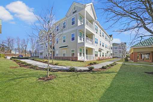 a large apartment building with a lawn and sidewalk in front of it at The Franklin at Hillsborough Apartments, Hillsborough, NJ 08844