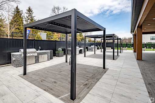 A modern outdoor seating area with a black metal roof and wooden flooring.