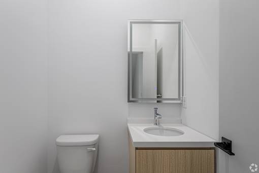 A bathroom with a toilet, sink and mirror.
