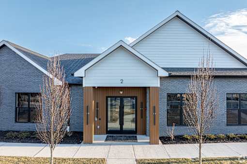 A modern building with a white front and a brown door.