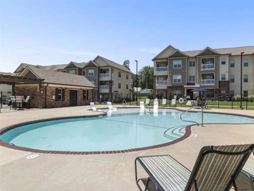 a swimming pool with an apartment building in the background at The Maddox Apartments, Centerton, AR