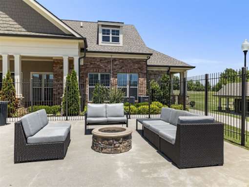a patio with chairs and a fire pit in front of a house at The Maddox Apartments, Centerton, AR