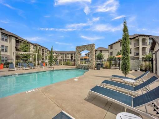 a resort style pool with lounge chairs and buildings in the background