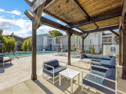a covered patio with chairs and tables next to a pool