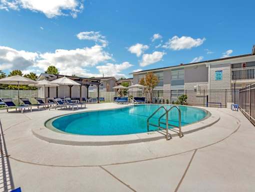 a swimming pool with chairs and umbrellas next to a building