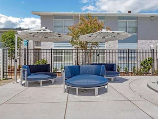 a patio with couches and umbrellas in front of a building
