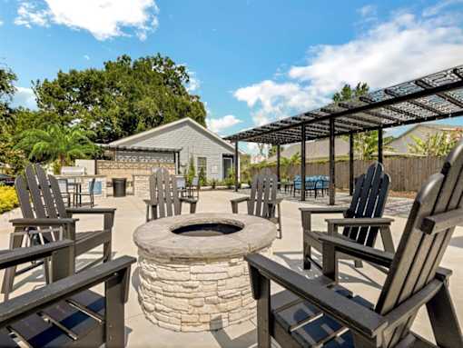 the fire pit is surrounded by wooden chairs and a pergola