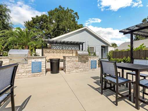 a patio with a table and chairs and a barbecue grill