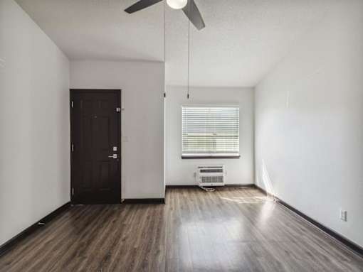 an empty living room with wood floors and a black door