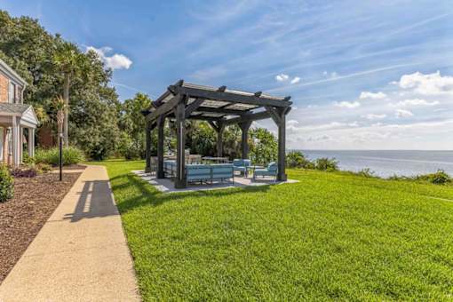 a gazebo with benches on the grass near the water