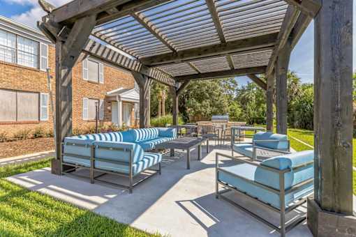 a covered patio with lounge chairs and a picnic table
