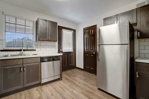 an empty kitchen with stainless steel appliances and wooden floors