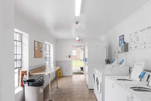 an empty laundry room with white appliances and a counter