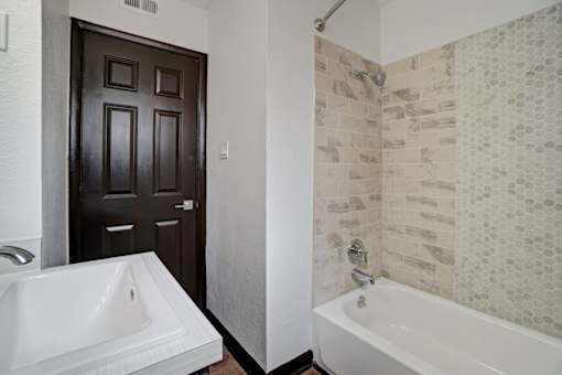 a bathroom with a tub and a sink and a door