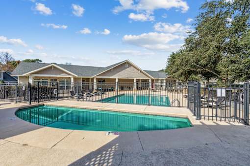 a swimming pool with a fence and a house behind it