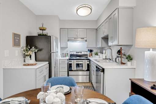 A modern kitchen with a dining table set for two. at The Beacon, Huntsville, AL, 35816