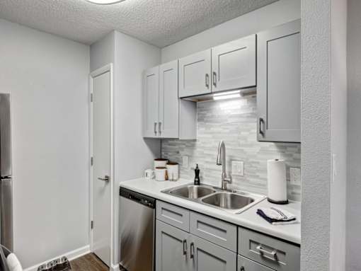 an empty kitchen with white cabinets and a stainless steel sink