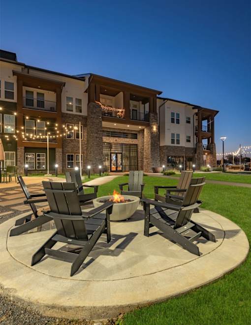 a patio with chairs and a fire pit in front of a building