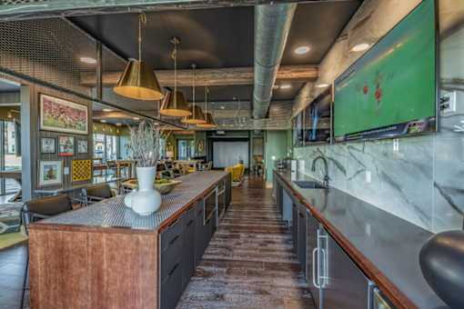 a restaurant with a long bar and a green painting on the wall