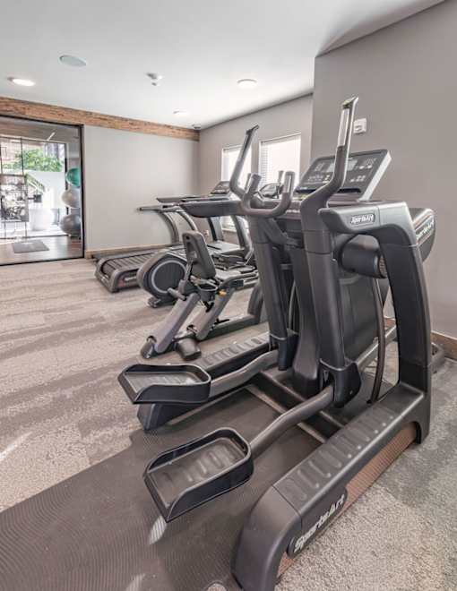 the gym is equipped with state of the art cardio equipment and a glass sliding door