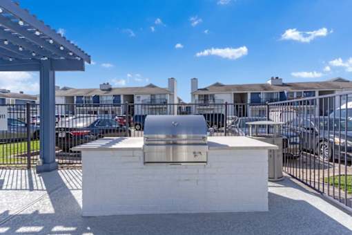 a bbq area in a parking lot with apartments in the background
