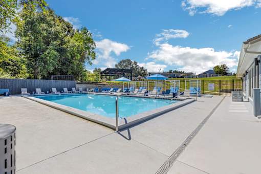 a resort style swimming pool with blue chairs around it at The Lorient Apartments, Pensacola, FL