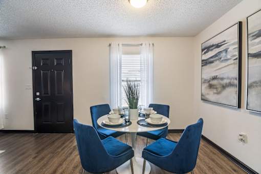 a dining room with a glass table and blue chairs at The Lorient Apartments, Pensacola, FL