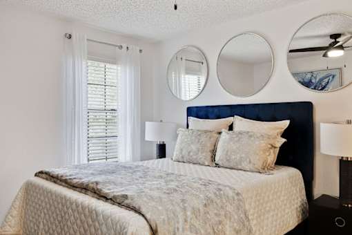 a bedroom with a bed and two mirrors above it at The Lorient Apartments, Florida