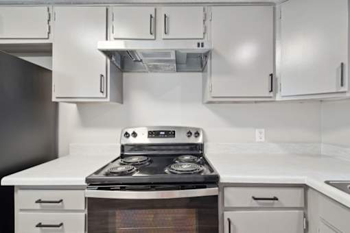 a kitchen with white cabinets and a stove top oven