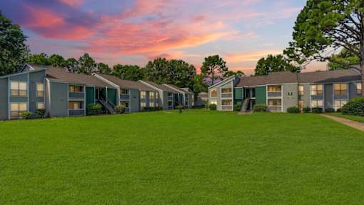 A row of houses with green lawns in front.