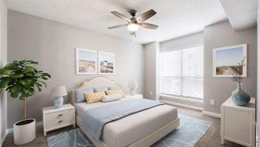 A bedroom with a bed, nightstands, a plant, and pictures on the wall.