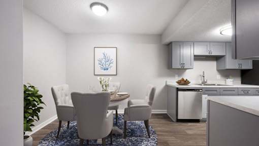 A dining area with a table set for two and a kitchen in the background.