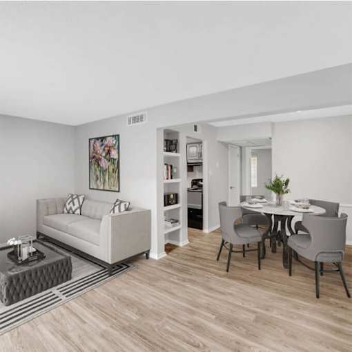 A living room with a white couch and a dining table with grey chairs.