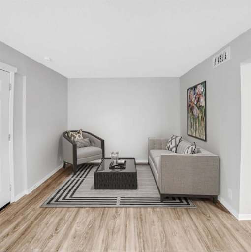 A living room with a grey sofa, a grey armchair, a black coffee table and a grey rug.