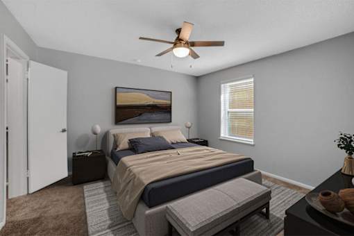 A bedroom with a bed, a bench, and a ceiling fan.