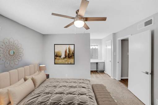 A bedroom with a large bed and a ceiling fan.