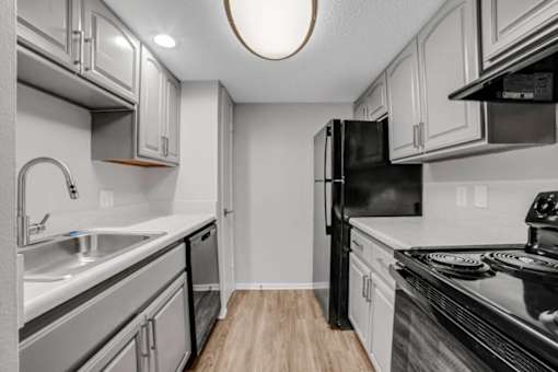 A kitchen with a black refrigerator and stove top oven.