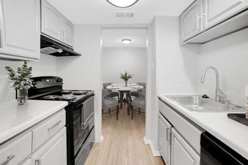 A kitchen with white cabinets and black appliances.